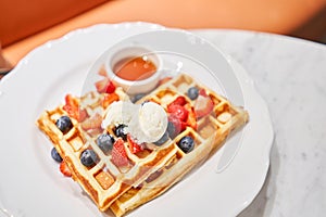 Classic Viennese waffles with ice cream, berries and Maple syrup. Breakfast in cafe. Table in the restaurant.
