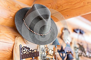 Classic vintage felt hat hanged on wall. Entrance of rustic wooden house . Welcome plate near door. Rural lifestyle background