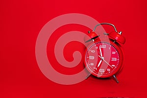 Classic vintage mechanical retro red alarm clock on red background at almost 7 o`clock with copy space. Isolated object.