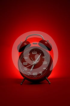 Classic vintage mechanical retro red alarm clock on red background at almost 7 o`clock with copy space. Isolated object. Concept