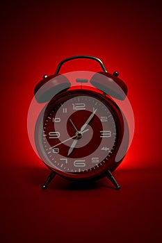 Classic vintage mechanical retro red alarm clock on red background at almost 7 o`clock with copy space. Isolated object. Concept o