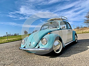 Classic VW beetle car against blue sky with wispy clouds