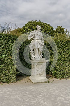 Classic white marble statue of woman with flute in green garden park. Ancient Roman or Greek woman stands on podium. the statue is