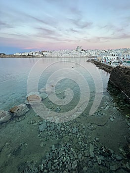 A classic white skyline contrasts a green harbour at sunset in Paros, Greece