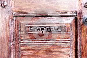 Classic wooden door with mail slot marked with the Spanish word cartas which means letters photo