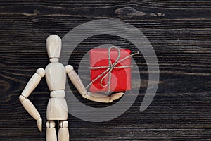 Classic wooden dummy holds red gift box.