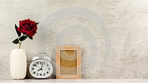 Classic wooden photo frame with alarm clock and a red rose. - blank space for message and advertising.