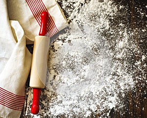 Classic wooden rolling pin and dusting of flour on wooden background