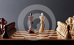 Classic Wooden Tournament chess set on black background. Two kings in center of board other pieces lined up