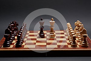 Classic Wooden Tournament chess set on black background. Two kings in centre of board other pieces lined up