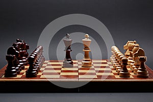 Classic Wooden Tournament chess set on black background. Two kings in centre of board other pieces lined up