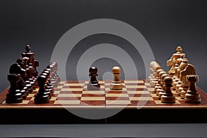 Classic Wooden Tournament chess set on black background. Two pawns in centre of board other pieces lined up