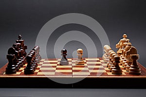 Classic Wooden Tournament chess set on black background. Two pawns in centre of board other pieces lined up