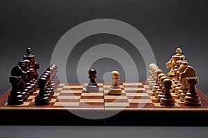 Classic Wooden Tournament chess set on black background. Two pawns in centre of board other pieces lined up