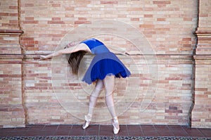 Classical ballet dancer with turkey blue tutu doing different poses and postures on a background of red bricks. Classical ballet