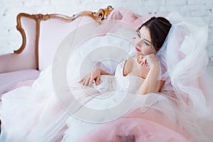 Classical beauty. Beautiful young woman with stylish brunette hair and elegant dress resting in luxury white classic