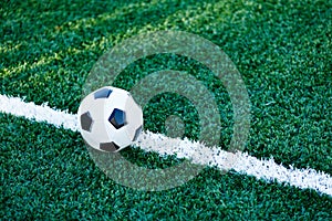 Classical black and white football ball on the green grass of the field. Soccer game, training, hobby concept.