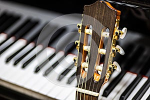 classical guitar against grand piano keys - musical instruments closeup - Spanish guitar with nylon strings for classical music