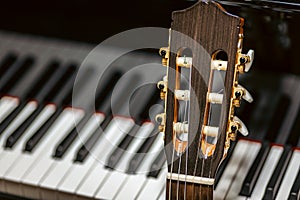 classical guitar against grand piano keys - musical instruments closeup - Spanish guitar with nylon strings for classical music