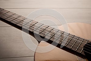 Classical guitar body and fretboard close up, on a light wood  background with copy space.