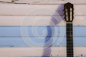 Classical guitar neck against pastel pink and blue beach hut