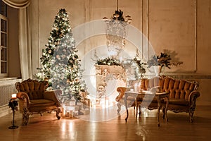 Classical interior of a white room with a decorated fireplace, sofa, Christmas tree, garlands, candles,lanterns, gifts