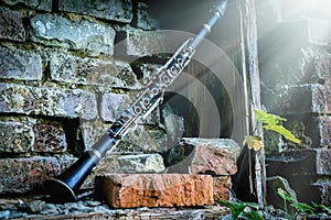 Classical music concept. Old clarinet in sunlight against background of ancient brick wall