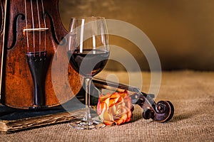 Classical old violins detail with red wine glass