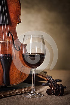 Classical old violin detail with red wine glass