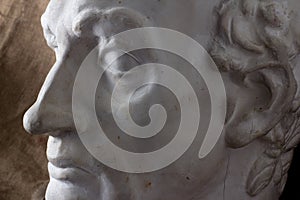 Classical plaster head bust against a background of rough brown fabric