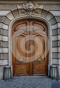 Gorgeous style arch with double door entrance of old building in Paris France. Vintage wooden doorway and stucco fretwork wall