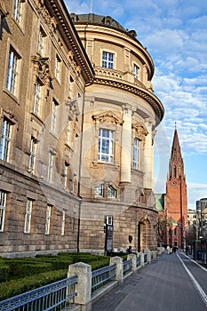 Classicist public building and tower of a neo-Gothic church on a street in the city center of Poznan