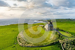 Classiebawn Castle on a backdrop of picturesque landscape of Mullaghmore Head. Spectacular sunset view with waves rolling ashore.