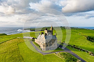 Classiebawn Castle on a backdrop of picturesque landscape of Mullaghmore Head. Spectacular sunset view with waves rolling ashore.