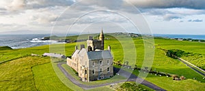 Classiebawn Castle on a backdrop of picturesque landscape of Mullaghmore Head. Spectacular sunset view with waves rolling ashore.