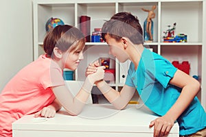 Classmates competing in arm wrestling during the break. Happy friends playing arm wrestle looking at each other