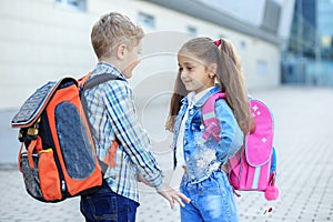 Classmates met in the schoolyard. Little boy and girl. The concept is back to school, study, friendship