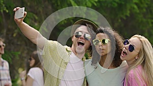 Classmates pulling funny faces and taking selfie at outdoor music festival