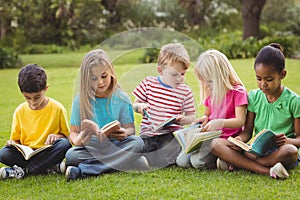 Classmates sitting in grass and reading books