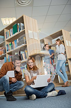 Classmates studying together on laptop in library