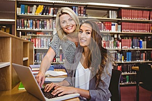Classmates using laptop and looking at camera