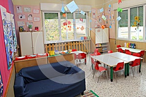 Classroom in a kindergarten with tables and chairs and blue sofa