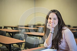 In the classroom - pretty female student with books working in a
