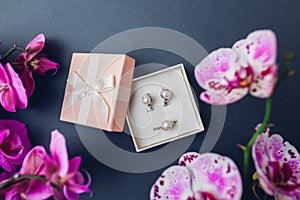 Classsic retro stylish jewelry. Silver ring earrings with pearls in gift box with purple orchid. Fashionable accessories