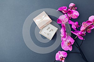 Classsic stylish female jewelry. Silver ring earrings with pearls in gift box with pink orchid. Fashionable accessories