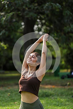 Classy Beautiful Woman In Gym Outfit Performing Surya Namaskar Exercise In Park