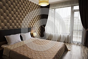 Classy bedroom interior design. Large bed, room with brown color tone. Windows with long curtains, drapery and sheers