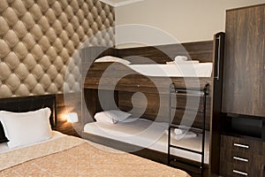 Classy hotel bedroom interior design. Large bed, bunk-beds. Family room with brown color tone furniture