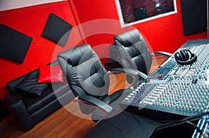 Classy professional recording studio setup, large desk with mixing console and two chairs, window for vocal booth, sofa