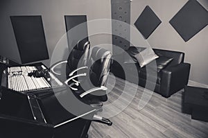 Classy professional recording studio setup, large desk with mixing console and two chairs, window for vocal booth, sofa